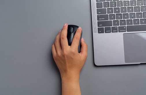 woman works with a laptop at home and holds a computer mouse in